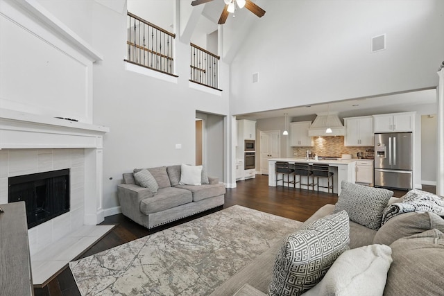 1617 Commons Way, Prosper, TX 75078 - living room featuring a ceiling fan, dark wood-style flooring, a fireplace, and a towering ceiling