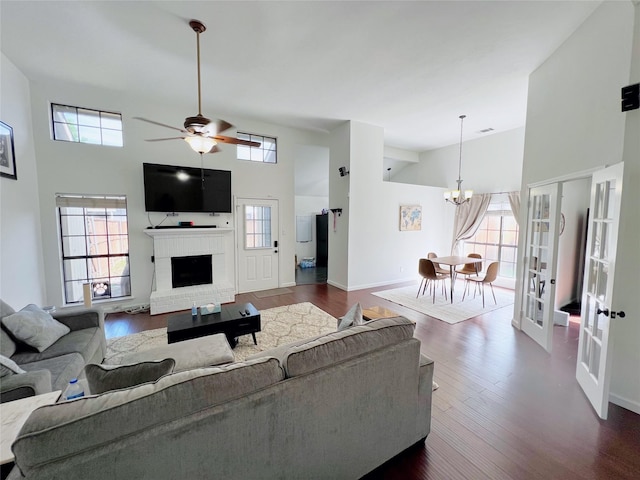 6828 Younger Dr, The Colony, TX 75056 - living room featuring a towering ceiling, plenty of natural light, a chandelier, a brick fireplace, and dark wood-type flooring