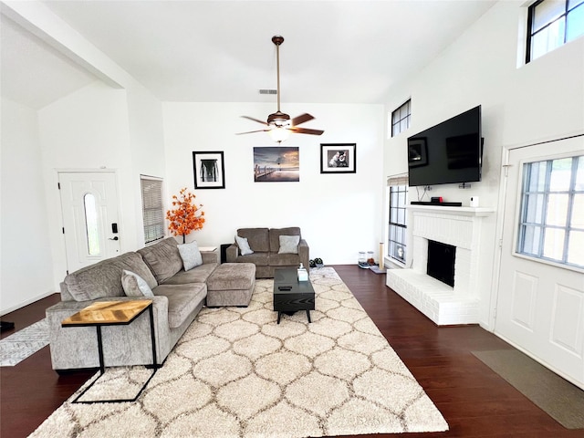 6828 Younger Dr, The Colony, TX 75056 - living area with a towering ceiling, dark wood-type flooring, a ceiling fan, and a brick fireplace