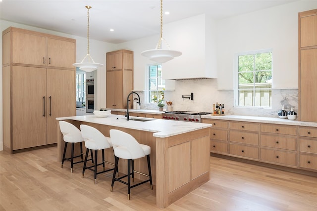3725 Stratford Ave, Highland Park, TX 75205 - kitchen featuring light brown cabinetry, light wood-style floors, a kitchen breakfast bar, tasteful backsplash, and recessed lighting