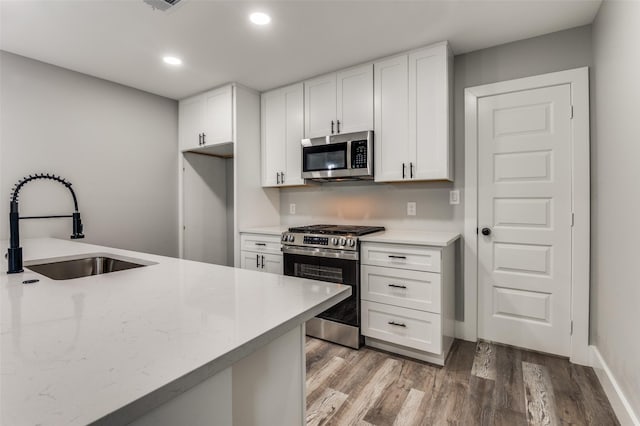 4131 Opal Ave, Dallas, TX 75216 - kitchen with appliances with stainless steel finishes, light wood finished floors, white cabinets, recessed lighting, and light stone counters