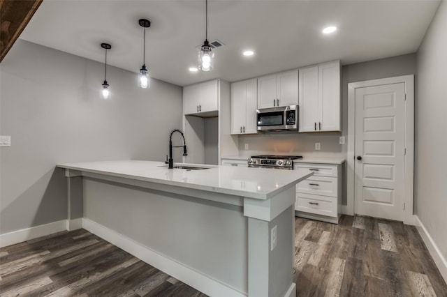 4131 Opal Ave, Dallas, TX 75216 - kitchen with appliances with stainless steel finishes, a peninsula, dark wood-type flooring, light countertops, and white cabinetry