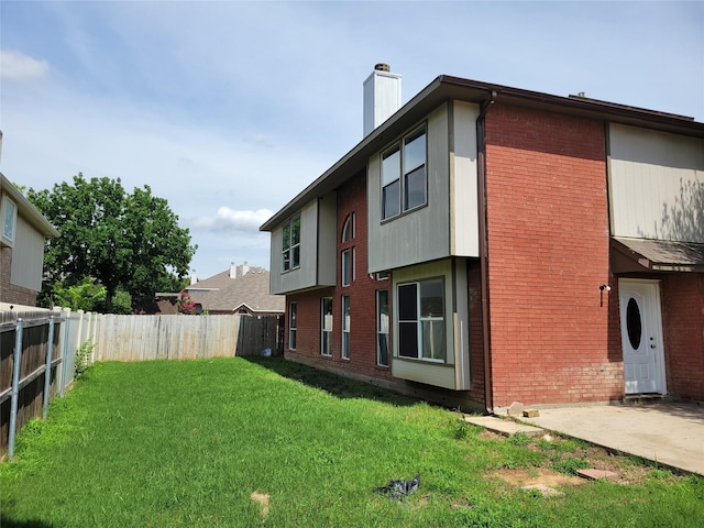 2001 Mark Twain Ln, Denton, TX 76210 - rear view of property featuring a fenced backyard, brick siding, a chimney, and a patio