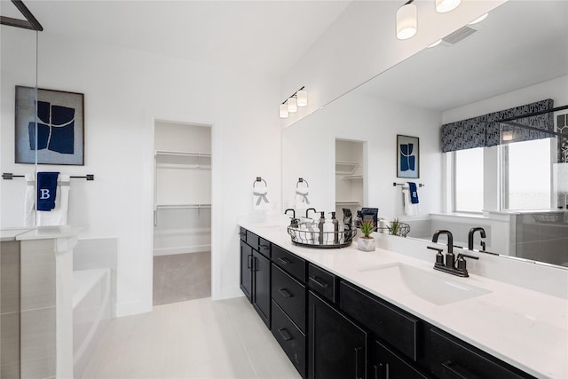 2420 Bernham Dr, Celina, TX 75009 - bathroom with double vanity, a walk in closet, a bath, and baseboards