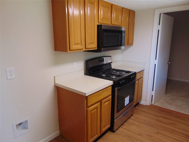 6207 Misty Wood Dr, Dallas, TX 75217 - kitchen with gas range, light countertops, light wood-style floors, and brown cabinetry