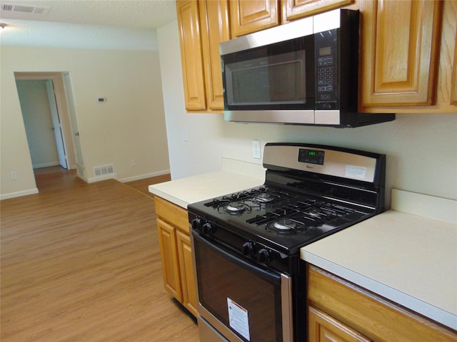 6207 Misty Wood Dr, Dallas, TX 75217 - kitchen with stainless steel appliances, light wood-style flooring, and light countertops