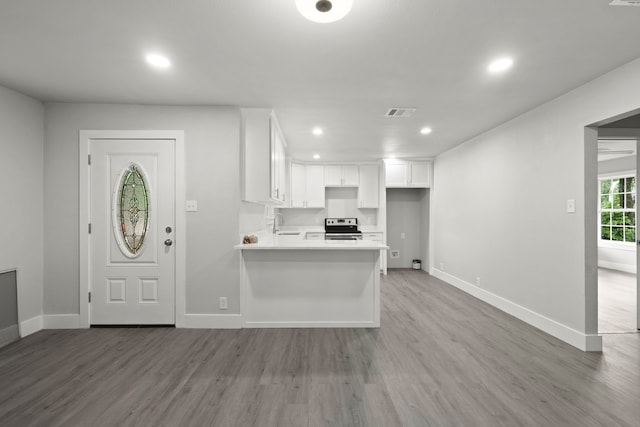 3624 Baylor St, Fort Worth, TX 76119 - kitchen with stainless steel range with electric stovetop, white cabinets, recessed lighting, wood finished floors, and light countertops