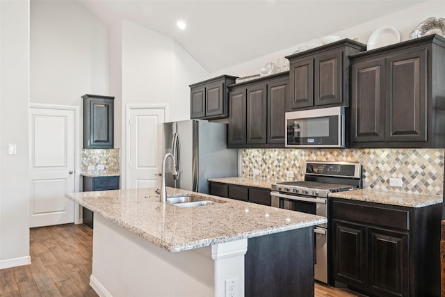8901 Thompson Rd, Argyle, TX 76226 - kitchen with stainless steel appliances, lofted ceiling, a kitchen island with sink, tasteful backsplash, and light wood finished floors
