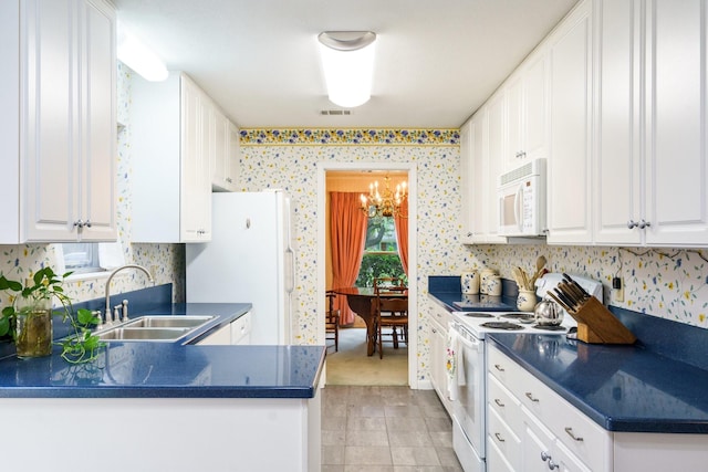 315 Ridgewood Dr, Richardson, TX 75080 - kitchen featuring white appliances, dark countertops, a chandelier, white cabinetry, and wallpapered walls