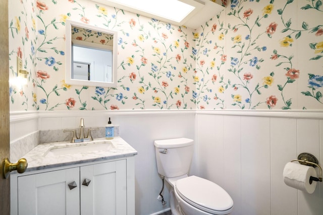 315 Ridgewood Dr, Richardson, TX 75080 - bathroom with wallpapered walls, wainscoting, and vanity