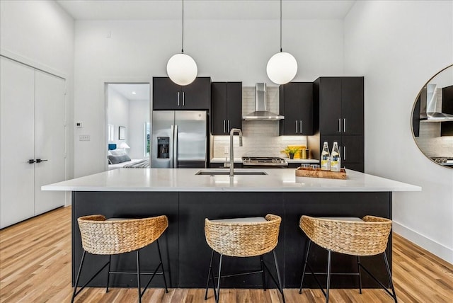 2138 Lovedale Ave Unit 102, Dallas, TX 75235 - kitchen featuring stainless steel refrigerator with ice dispenser, wall chimney exhaust hood, dark cabinetry, light countertops, and a high ceiling