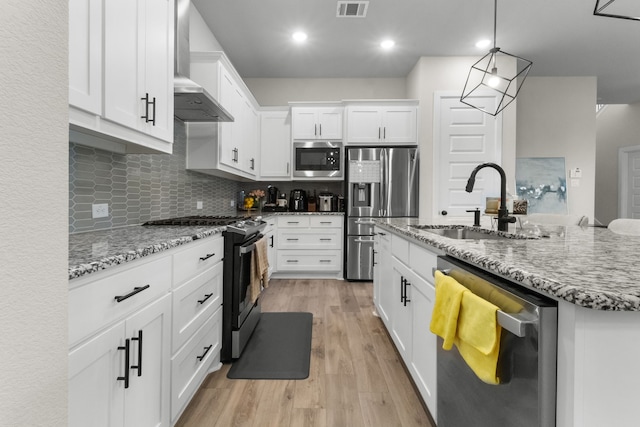 711 Prairie Falcon Dr, Arlington, TX 76005 - kitchen featuring appliances with stainless steel finishes, wall chimney exhaust hood, light wood-type flooring, white cabinetry, and light stone counters