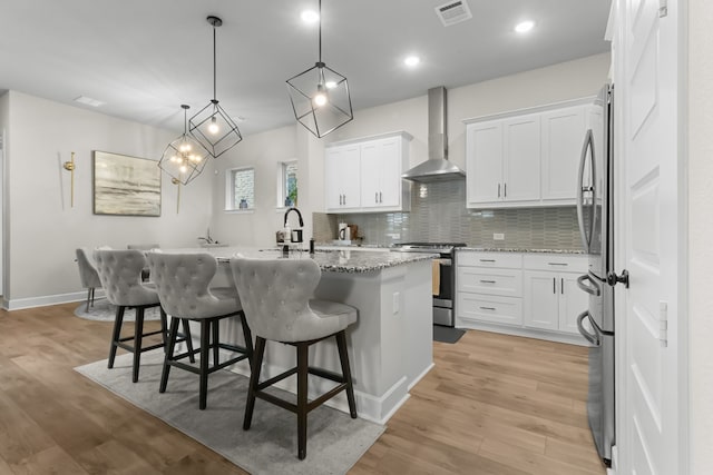 711 Prairie Falcon Dr, Arlington, TX 76005 - kitchen with wall chimney exhaust hood, stainless steel appliances, a kitchen island with sink, tasteful backsplash, and a breakfast bar area