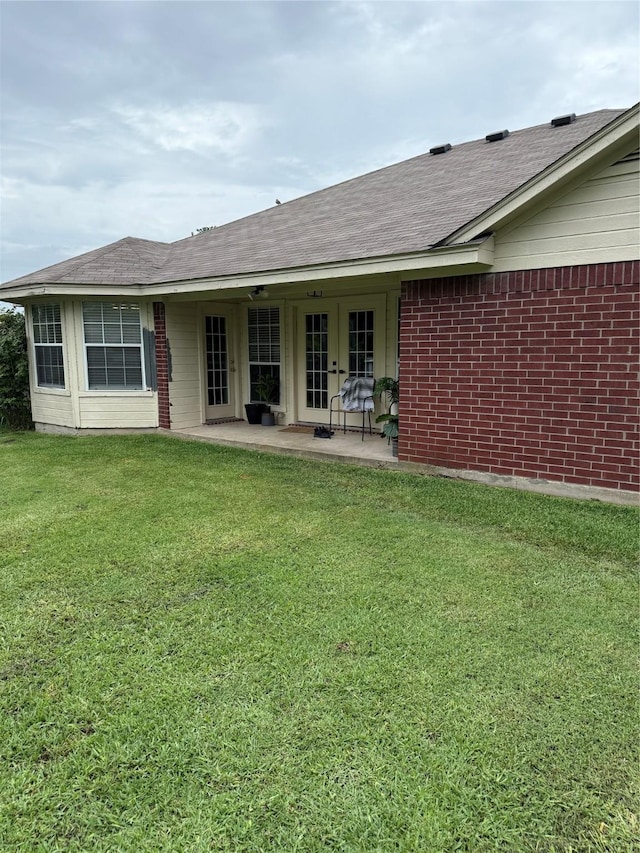907 Dogwood St, Waco, TX 76706 - rear view of property featuring french doors, a lawn, a patio area, brick siding, and roof with shingles