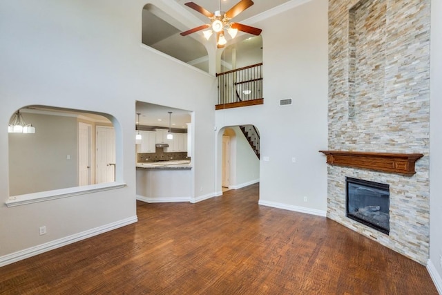 4517 Copeland Dr, Plano, TX 75024 - unfurnished living room featuring a ceiling fan, a stone fireplace, dark wood-type flooring, arched walkways, and a towering ceiling