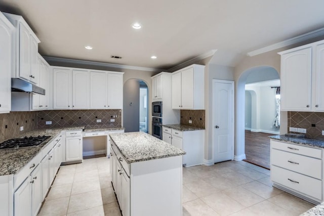 4517 Copeland Dr, Plano, TX 75024 - kitchen featuring arched walkways, appliances with stainless steel finishes, backsplash, under cabinet range hood, and ornamental molding