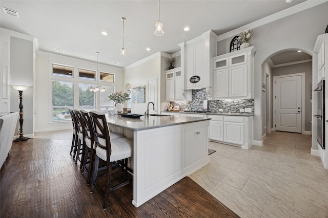 4513 Donnoli Dr, Flower Mound, TX 75022 - kitchen with ornamental molding, arched walkways, decorative backsplash, an island with sink, and white cabinets