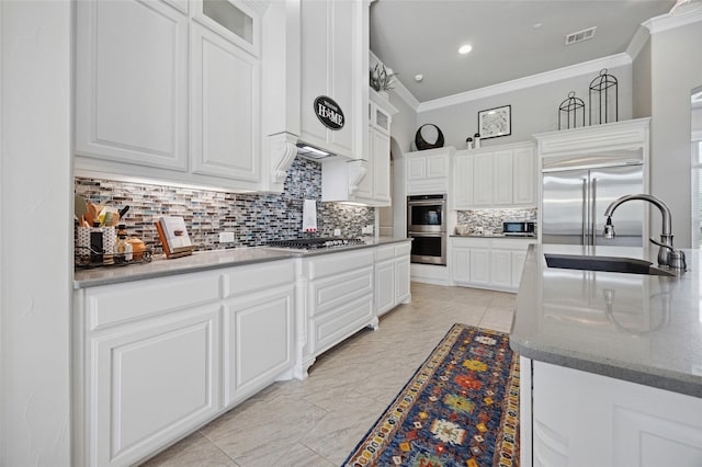 4513 Donnoli Dr, Flower Mound, TX 75022 - kitchen with appliances with stainless steel finishes, ornamental molding, tasteful backsplash, white cabinetry, and glass insert cabinets