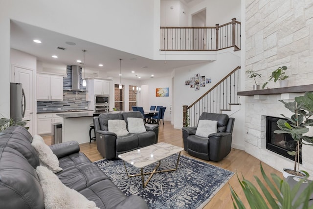 2464 Castle Ridge Dr, Richardson, TX 75080 - living room with stairway, light wood finished floors, a fireplace, a high ceiling, and recessed lighting