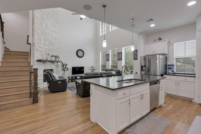 2464 Castle Ridge Dr, Richardson, TX 75080 - kitchen with appliances with stainless steel finishes, dark countertops, light wood finished floors, open floor plan, and white cabinetry