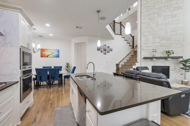 2464 Castle Ridge Dr, Richardson, TX 75080 - kitchen with stainless steel appliances, light wood finished floors, white cabinets, a fireplace, and dark countertops