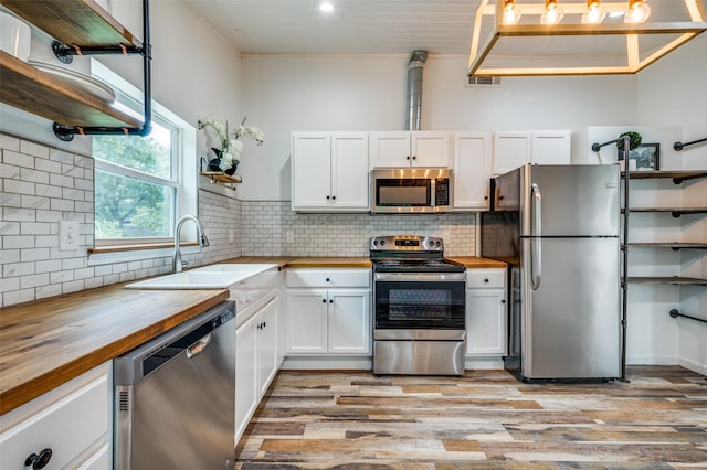 1505 W St, Mckinney, TX 75069 - kitchen with wooden counters, stainless steel appliances, white cabinets, light wood finished floors, and recessed lighting