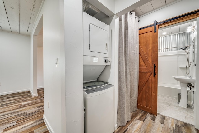 1505 W St, Mckinney, TX 75069 - laundry room with stacked washer / drying machine, wood finished floors, and a barn door