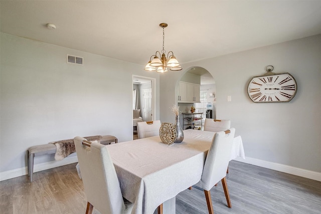1343 Fernwood Ave, Dallas, TX 75216 - dining area featuring arched walkways, light wood-type flooring, and a chandelier