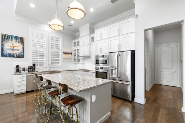 705 Wolcott Ln, Plano, TX 75074 - kitchen featuring appliances with stainless steel finishes, ornamental molding, glass insert cabinets, a center island, and white cabinets
