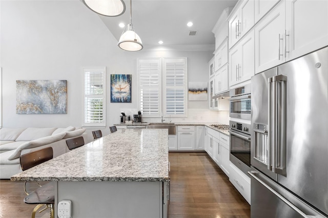 705 Wolcott Ln, Plano, TX 75074 - kitchen featuring appliances with stainless steel finishes, a kitchen island, a breakfast bar area, light stone counters, and recessed lighting
