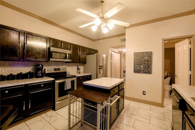 2315 Rockhill Rd, Mckinney, TX 75072 - kitchen with stainless steel appliances, light marble finish floors, ornamental molding, ceiling fan, and light countertops