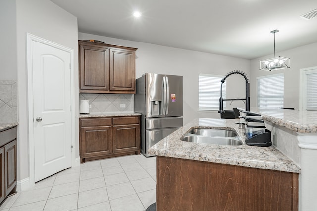 680 Navasota Dr, Crandall, TX 75114 - kitchen with stainless steel refrigerator with ice dispenser, light tile patterned flooring, decorative backsplash, hanging light fixtures, and light stone countertops