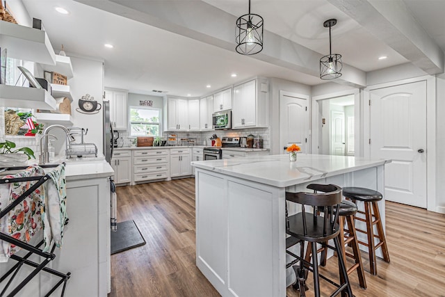 3135 Brazos River Dr, Granbury, TX 76048 - kitchen with appliances with stainless steel finishes, light wood-style flooring, tasteful backsplash, a kitchen bar, and white cabinetry
