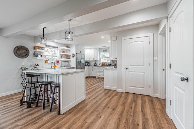 3135 Brazos River Dr, Granbury, TX 76048 - kitchen featuring stainless steel fridge, a peninsula, white cabinets, wood finished floors, and a breakfast bar