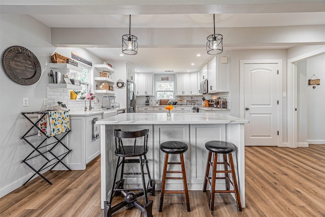 3135 Brazos River Dr, Granbury, TX 76048 - kitchen featuring decorative backsplash, wood finished floors, white cabinetry, open shelves, and a breakfast bar