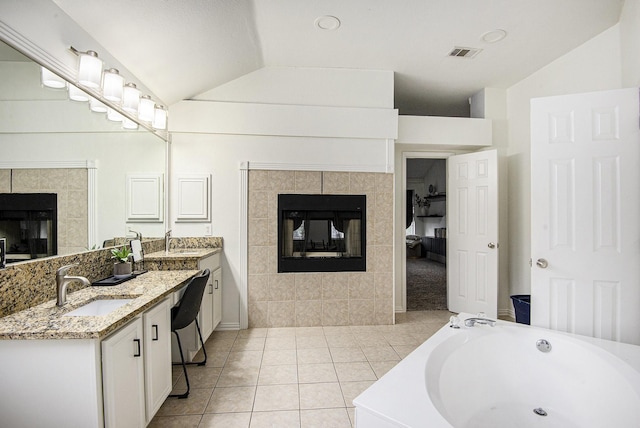 6833 Permian Ln, Fort Worth, TX 76137 - full bathroom featuring a tile fireplace, vaulted ceiling, double vanity, a bath, and tile patterned floors