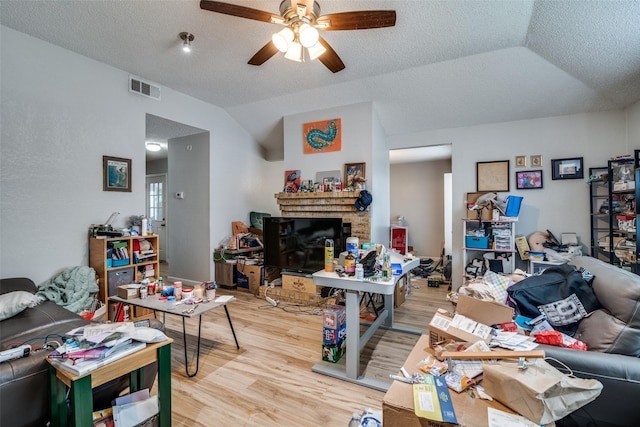1612 Hackamore St, Mesquite, TX 75149 - living room featuring lofted ceiling, light wood-type flooring, a ceiling fan, a brick fireplace, and a textured ceiling