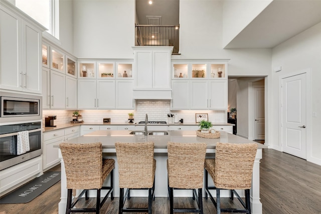 3900 Brazoria Dr, Prosper, TX 75078 - kitchen featuring stainless steel appliances, a towering ceiling, backsplash, a kitchen breakfast bar, and a kitchen island with sink