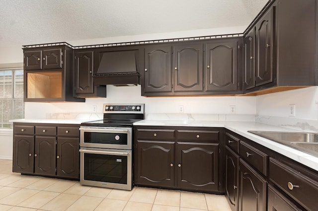 2515 High Pointe Blvd, Mckinney, TX 75071 - kitchen with range with two ovens, custom range hood, light tile patterned flooring, light countertops, and dark brown cabinetry