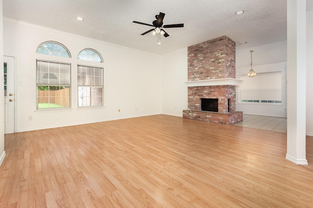 2515 High Pointe Blvd, Mckinney, TX 75071 - unfurnished living room with a textured ceiling, ceiling fan, wood finished floors, a brick fireplace, and ornamental molding