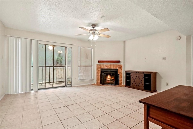 11460 Audelia Rd Unit 172, Dallas, TX 75243 - unfurnished living room featuring ceiling fan, a textured ceiling, a lit fireplace, and light tile patterned flooring