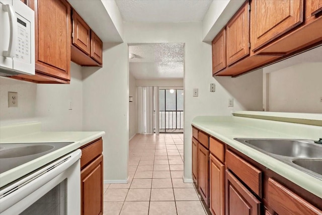 11460 Audelia Rd Unit 172, Dallas, TX 75243 - kitchen featuring white appliances, light tile patterned floors, brown cabinets, light countertops, and a textured ceiling