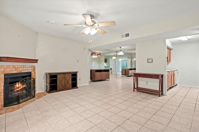 11460 Audelia Rd Unit 172, Dallas, TX 75243 - unfurnished living room with ceiling fan, a brick fireplace, light tile patterned floors, and a textured ceiling