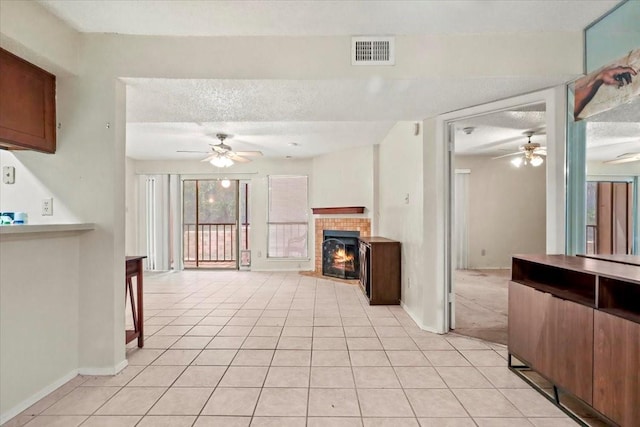 11460 Audelia Rd Unit 172, Dallas, TX 75243 - unfurnished living room featuring ceiling fan, a tile fireplace, light tile patterned floors, and a textured ceiling