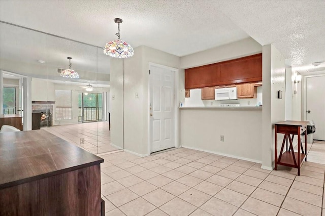 11460 Audelia Rd Unit 172, Dallas, TX 75243 - kitchen featuring white microwave, a textured ceiling, light tile patterned flooring, a fireplace, and open floor plan