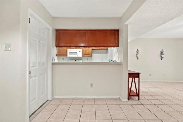 11460 Audelia Rd Unit 172, Dallas, TX 75243 - kitchen featuring white microwave, light tile patterned floors, and light countertops