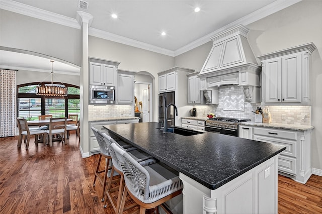 2427 Remuda Dr, Sherman, TX 75092 - kitchen with appliances with stainless steel finishes, dark wood-type flooring, an island with sink, backsplash, and arched walkways
