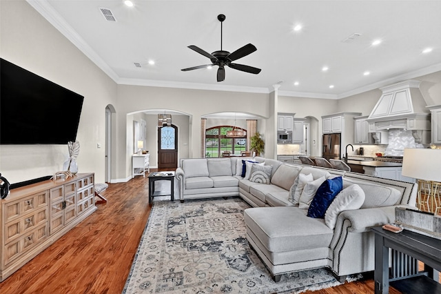 2427 Remuda Dr, Sherman, TX 75092 - living room featuring arched walkways, a ceiling fan, recessed lighting, wood finished floors, and ornamental molding