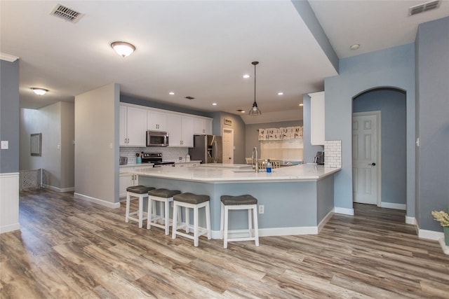 5216 Copper Creek Dr, Fort Worth, TX 76244 - kitchen featuring appliances with stainless steel finishes, a peninsula, light wood-style flooring, white cabinetry, and recessed lighting
