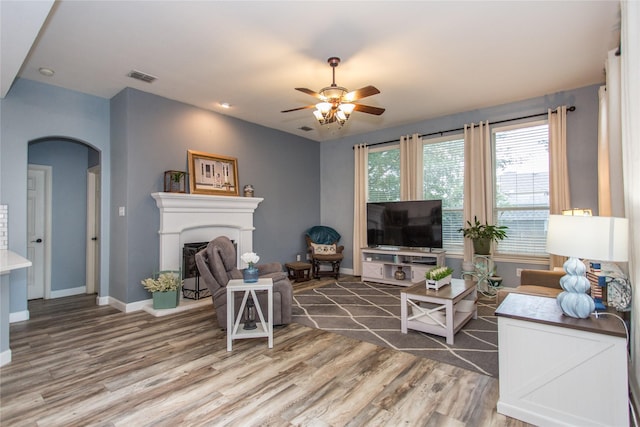 5216 Copper Creek Dr, Fort Worth, TX 76244 - living area featuring arched walkways, light wood-style flooring, ceiling fan, and a fireplace with raised hearth